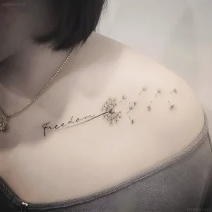 Женская татуировка на ключице с надписью Freedom и улетящими семенами одуванчика