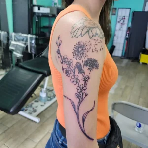 Женская татуировка с одуванчиком на плече в стиле blackwork