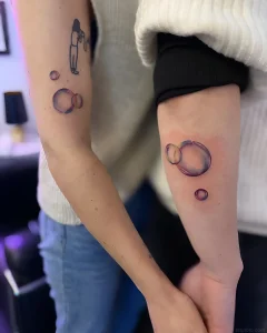 Два человека показывают татуировки с изображением мыльных пузырей на предплечьях