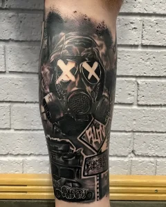 Детальная фотография реалистичной татуировки на ноге: противогаз с крестами вместо глаз, дым и дорожный знак с предупреждением о зомби