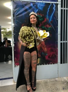 Победительница конкурса Miss Tattoo Эстеффани с татуировками на ногах и руках, в короне и с большим золотым призом