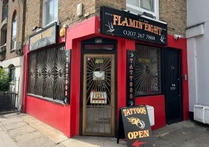 Ярко-красная студия татуировок Flamin' Eight в Лондоне с вывеской и открытой дверью, ставшая местом паломничества болельщиков «Арсенала» после победы в АПЛ