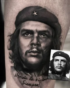 Черно-белая реализм татуировка портрета Че Гевары на ноге с подписью Hasta la Victoria Siempre и вставленным оригинальным фото для сравнения