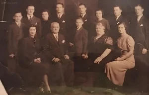 Винтажное сепия-фотография большой семьи в формальной одежде начала 20 века, сидящих и стоящих в два ряда, демонстрирующая традиционные ценности ирландских предков