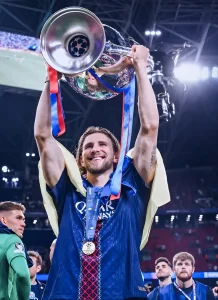 Футболист Андрэас Рахбек поднимает кубок Лиги Чемпионов, на его правой руке видна татуировка