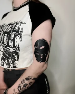 Татуировка черной маски с молнией на предплечье в стиле blackwork, фото в контексте статьи о значении BDSM тату