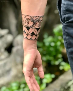 Детальное фото татуировки в виде браслета на запястье, состоящей из верхней части с волнами и нижней части с геометрическим плетением