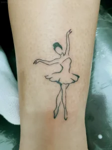 Черно-белая контурная татуировка силуэта балерины в пачке на светлой коже предплечья
