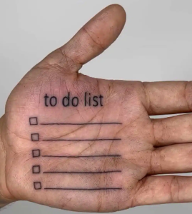 Крупный план мужской ладони с татуировкой в виде списка дел: надпись to do list и пять пустых строк с галочками