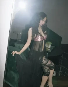 Дженни из BLACKPINK в черном кружевном платье и туфлях на каблуках, демонстрирующая новую татуировку ангела на стопе