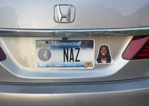 Задняя часть серебристого автомобиля Honda с номером Minnesota и стикером с портретом Наз Рид