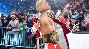 WWE-звезда Коди Роудс в красном плаще с чемпионским поясом на поясе, смотрит вверх, демонстрируя татуировку на шее — американский флаг в стиле old school, который он назвал своим величайшим сожалением в жизни
