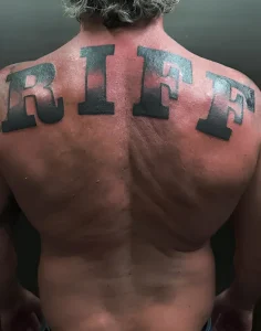 Спина Доминика Пёрселла с новой татуировкой RIFF крупными чёрными буквами в стиле bold lettering blackwork с градиентным затуханием