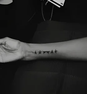 Чёрно-белое фото внутренней стороны предплечья Иман с минималистичной blackwork-татуировкой из пяти звёзд в ряд — трибьют к последнему альбому Дэвида Боуи Blackstar