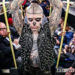 Фото тату: Мужчина с татуировкой в виде черепа на лице, в метро. Черно-белый стиль, провокационный образ, татуировки на теле.