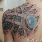 Фото тату биомеханики на плече. Металлические детали, провода, голубой свет, реалистичный рисунок. Черно-серые тона с акцентами.